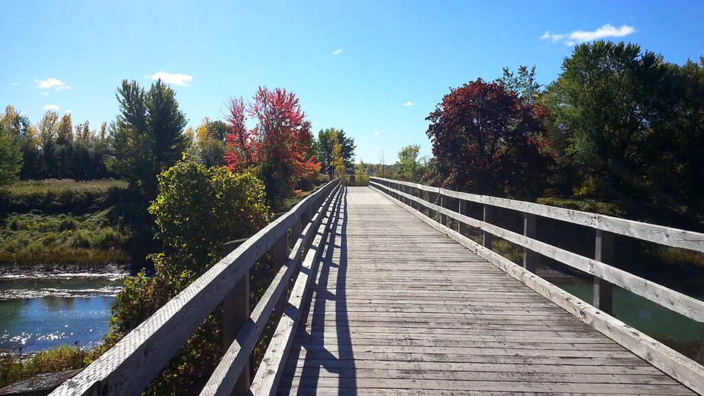 Passerelle de bois entourée de feuillage rouge au parc national des Îles-de-Boucherville, idéale pour le vélo d'automne au Québec