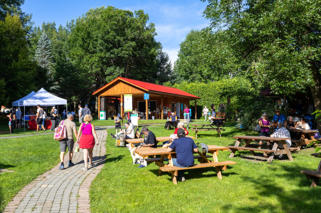 Visiteurs et tables à pique-nique au parc des Lions pendant le Marché public de Compton