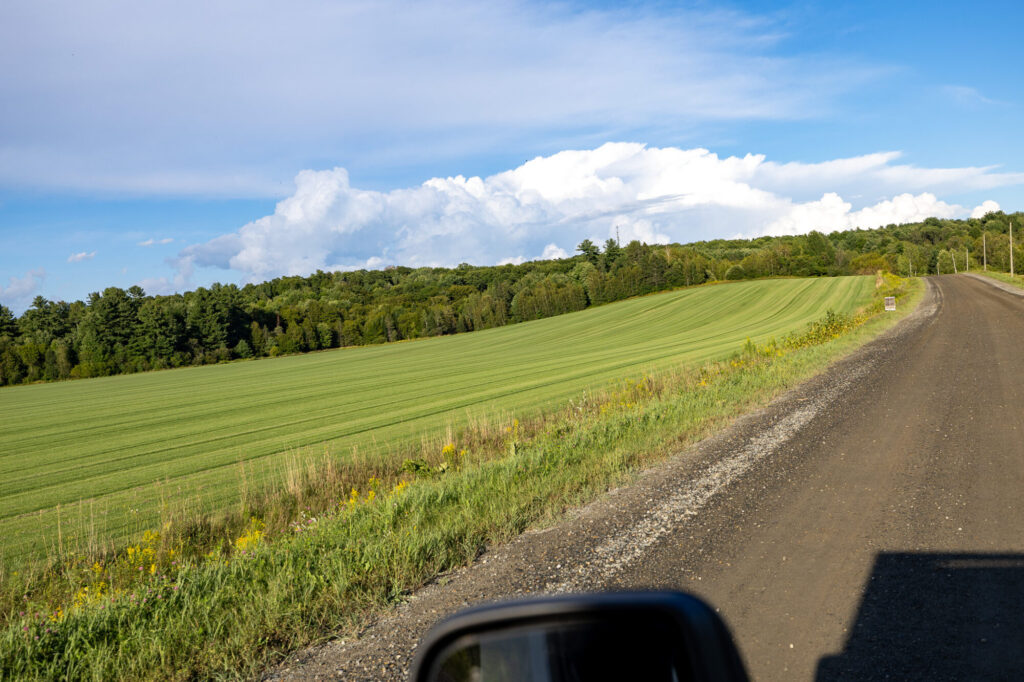 Route de campagne longeant un champ près de Coaticook