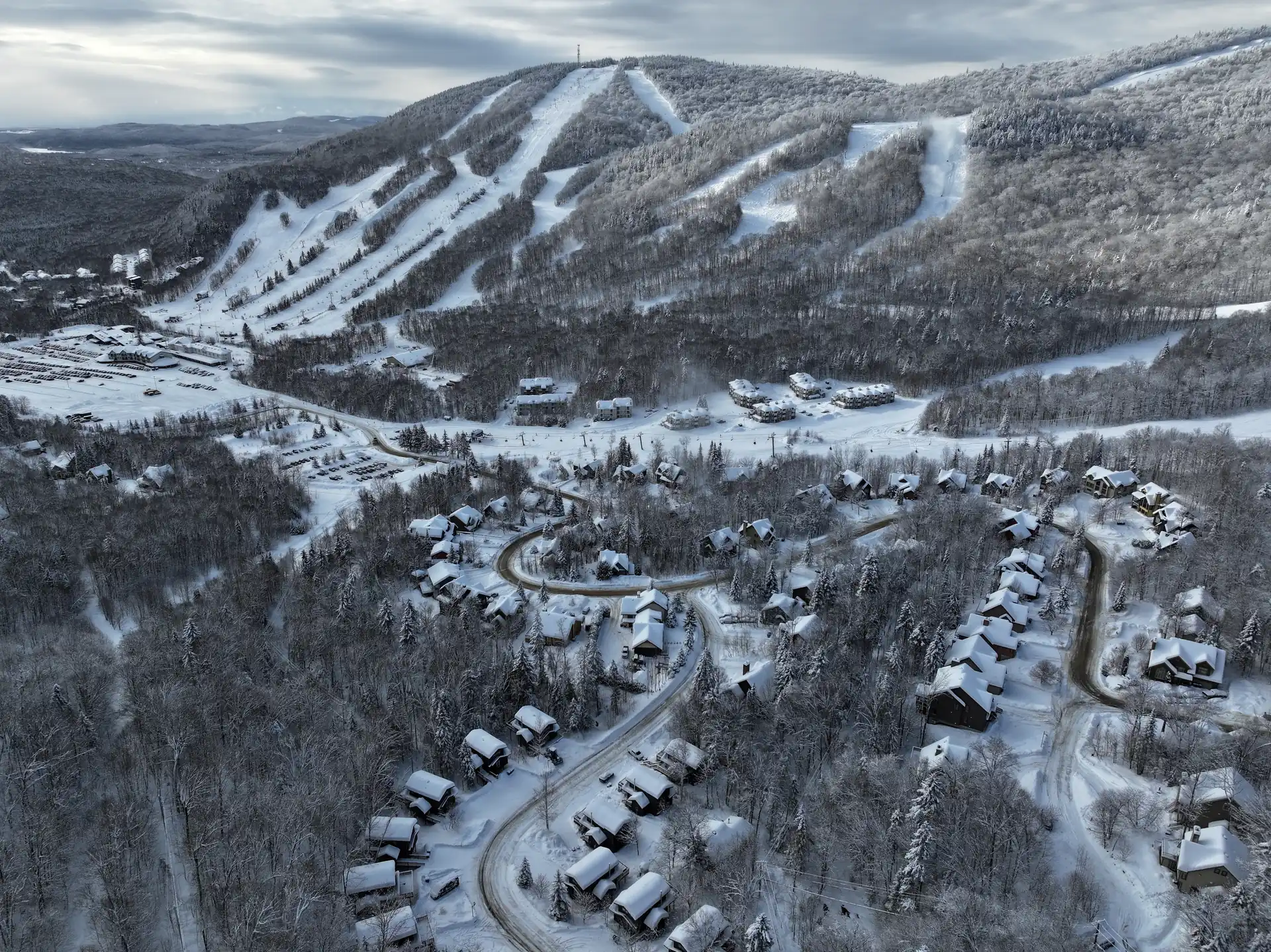 Vue aérienne de Stoneham en hiver : pistes de ski et chalets enneigés, une activité en famille dans la Jacques-Cartier