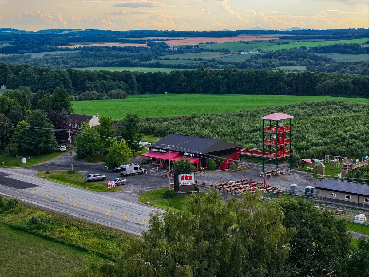 Vue aérienne d'un verger de Compton avec sa boutique et sa tour d'observation rouge, champs et collines au loin