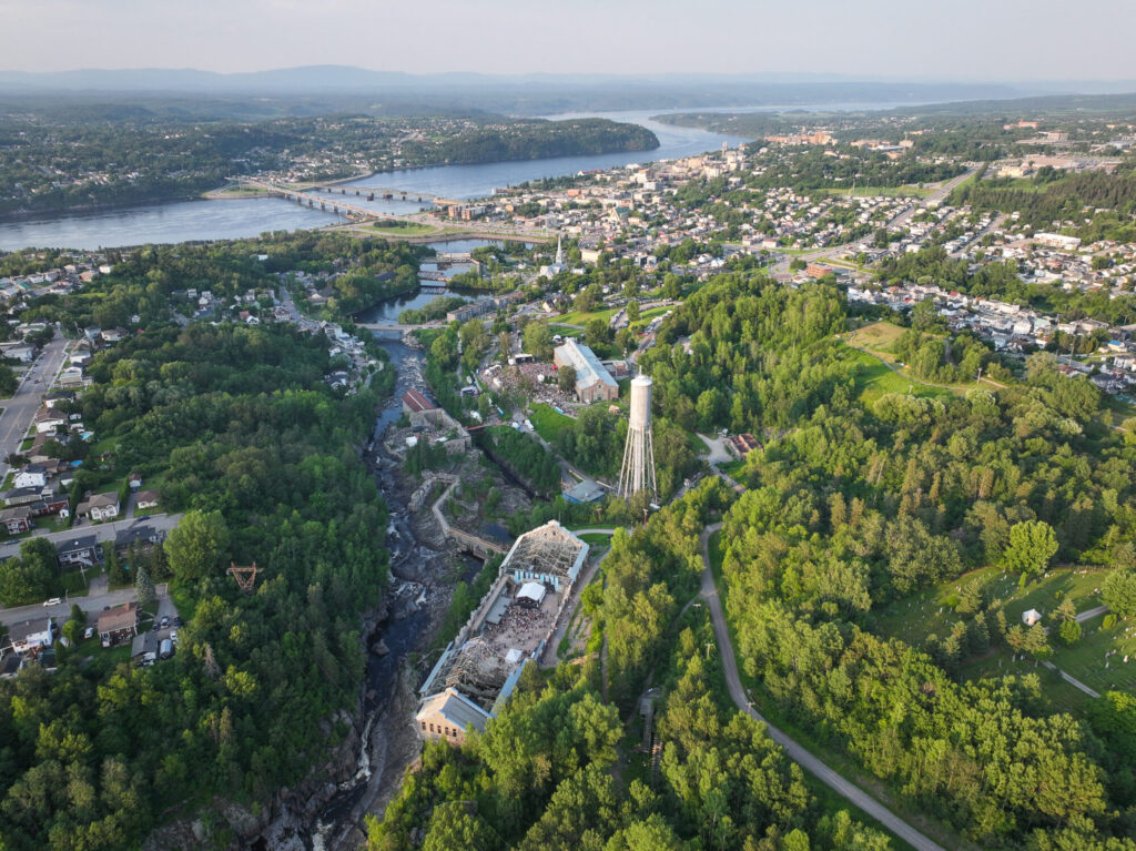 Panorama aérien de Chicoutimi montrant la Pulperie, la rivière Chicoutimi, le centre-ville et la rivière Saguenay