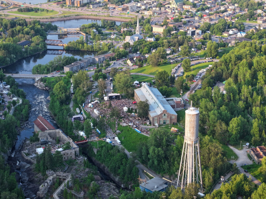 Vue aérienne de la foule rassemblée devant la scène du festival La Noce sur le site de la Pulperie de Chicoutimi