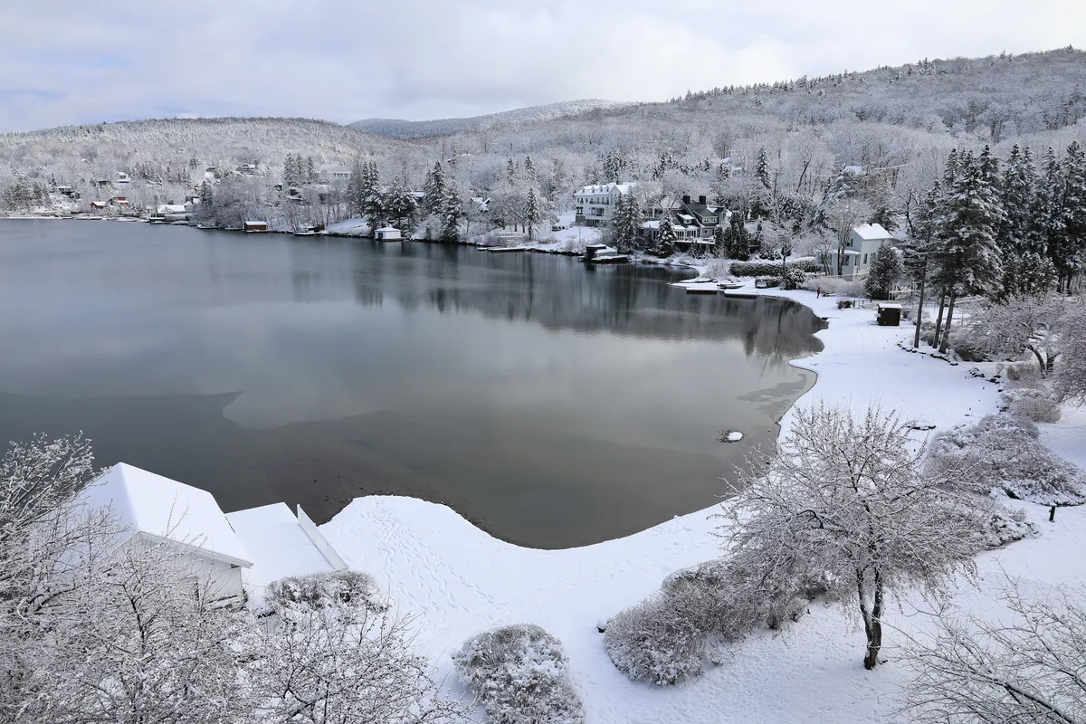Rive du lac Beauport sous la première neige, arbres givrés et maisons au bord de l'eau