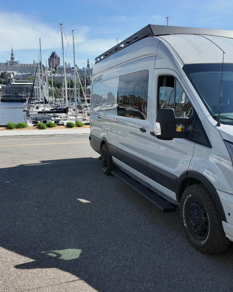 Van aménagé gris garé près de la marina du Vieux-Port de Québec, avec le Château Frontenac en arrière-plan