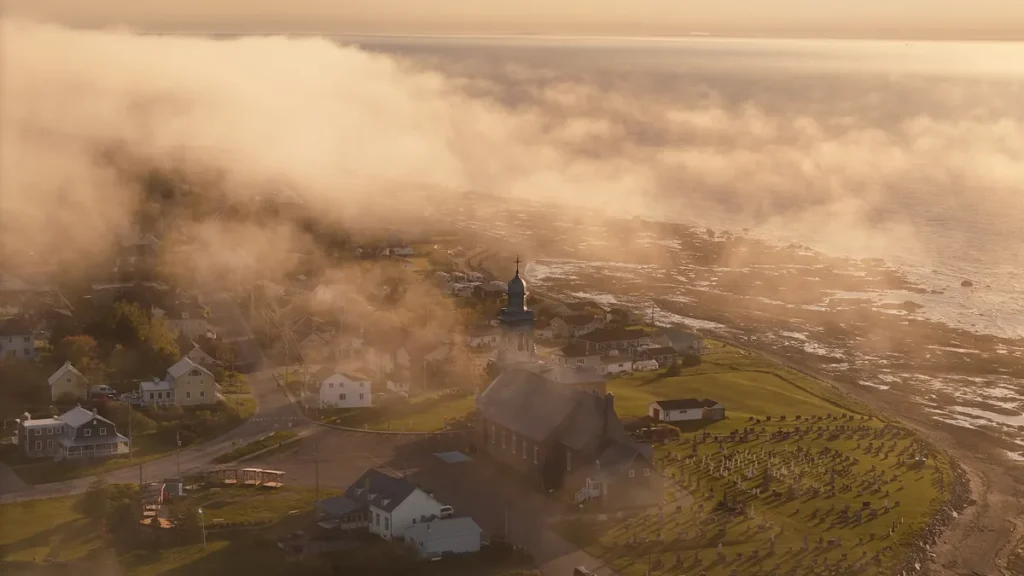 Vue aérienne de Sainte-Luce, départ de la Route des Monts Notre-Dame, brume dorée sur le fleuve en soirée d'été