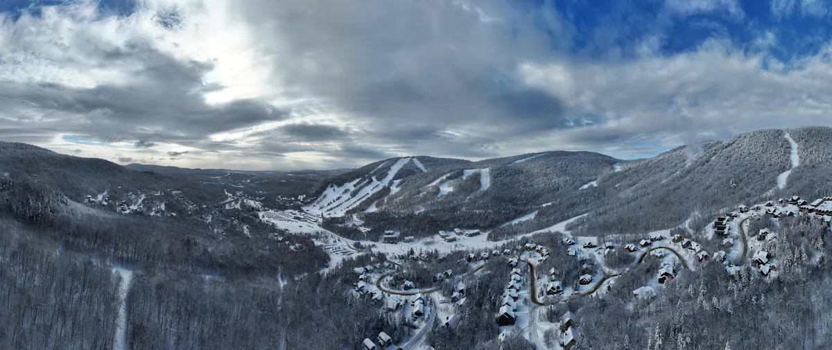 Panorama aérien de la vallée de Stoneham en hiver, montagnes enneigées et chalets dans la forêt