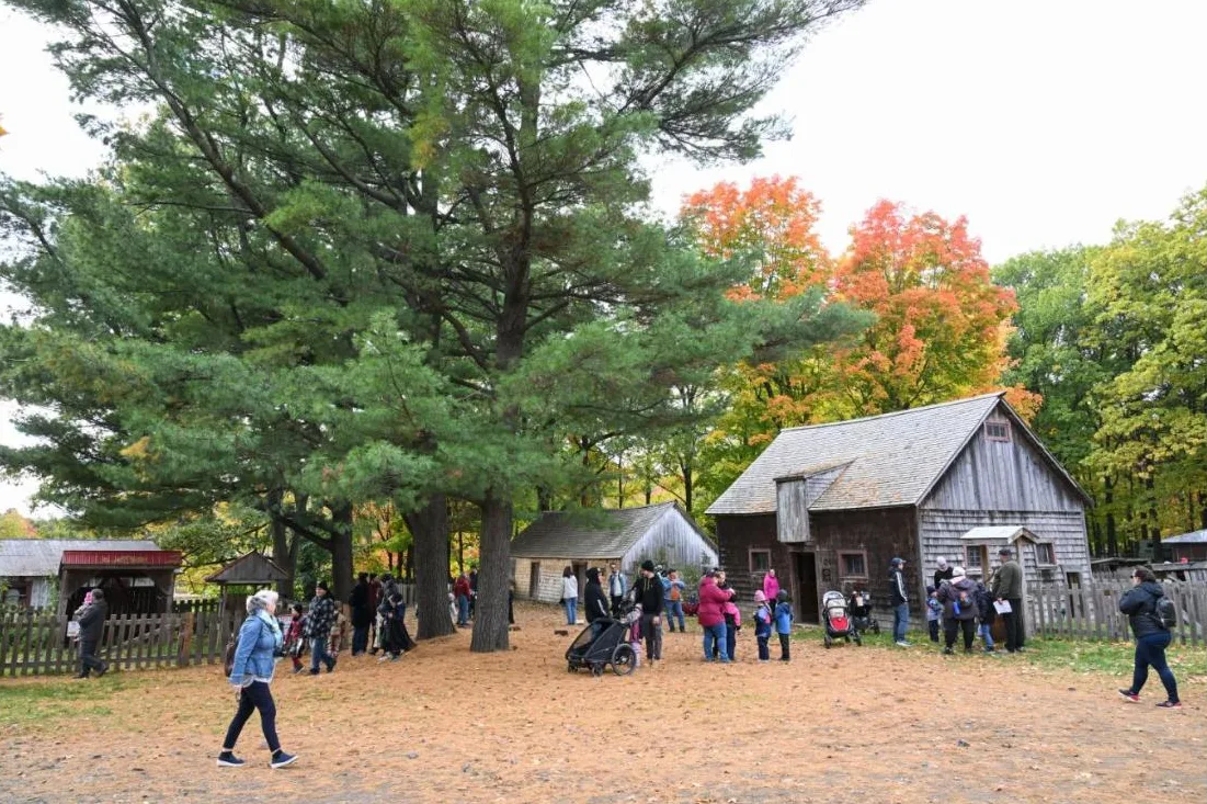 Familles qui se promènent entre les bâtiments d'époque du Village Québécois d'Antan à Drummondville en automne