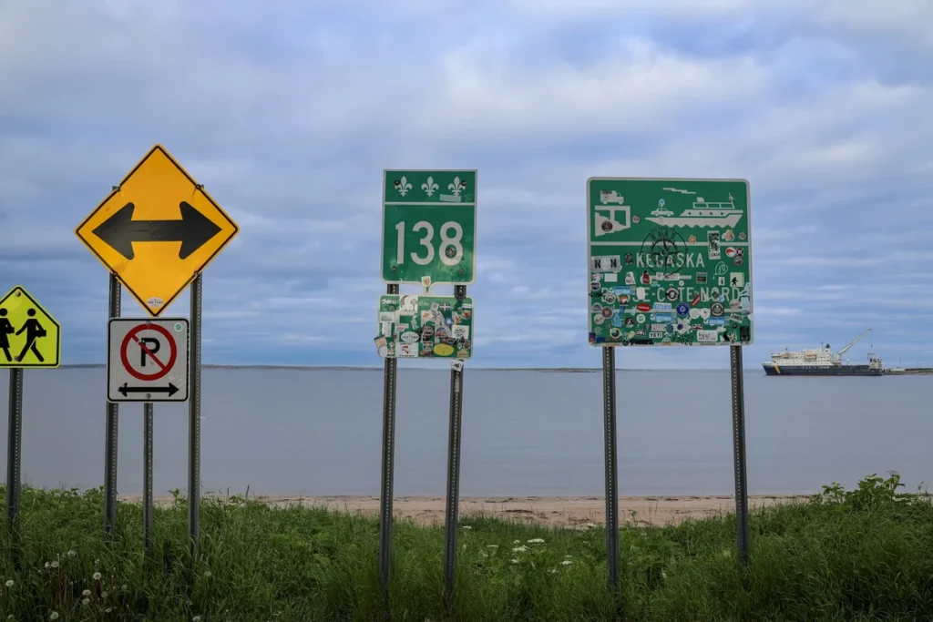 Panneaux de la route 138 à Kegaska, avec le Bella Desgagnés au large
