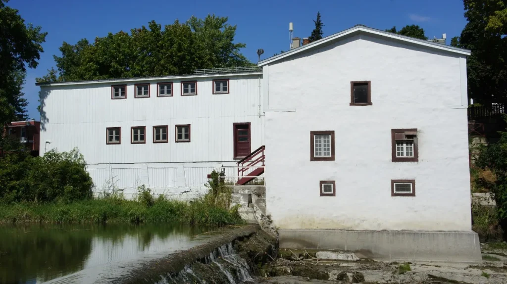 Façade blanche du moulin Légaré, au bord de la rivière du Chêne dans le Vieux-Saint-Eustache