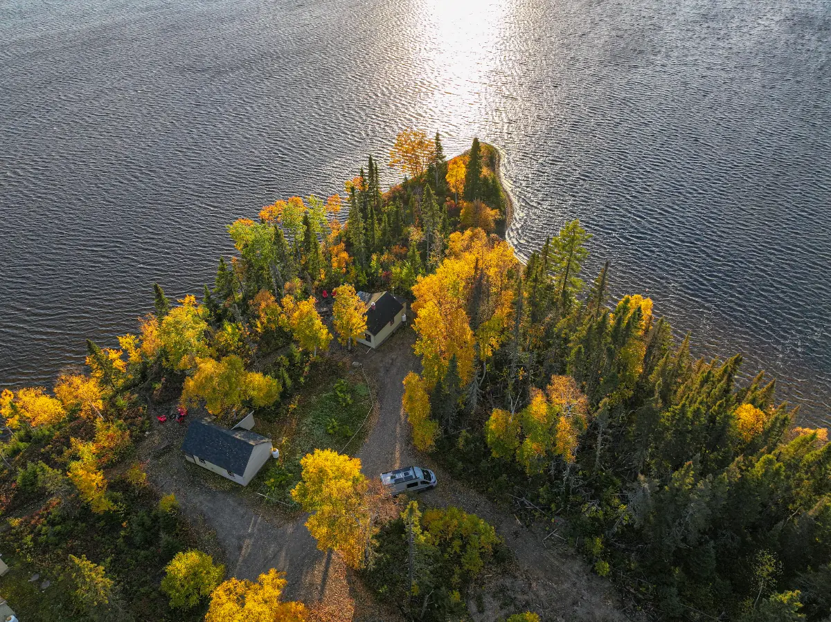 Chalets sur une pointe boisée du lac Chigoubiche à l'automne, vus du ciel
