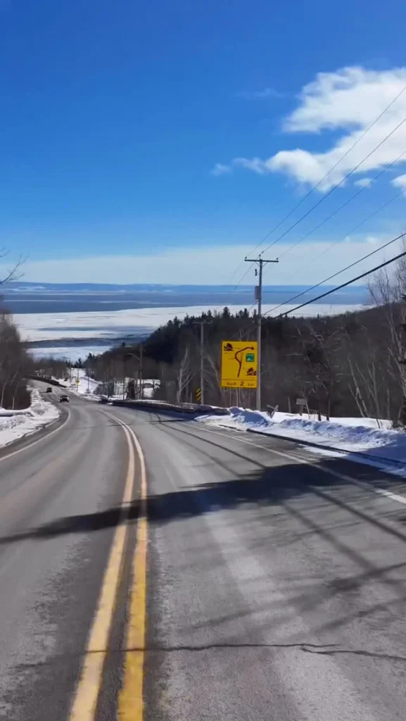 Route enneigée de Charlevoix avec le fleuve à l'horizon