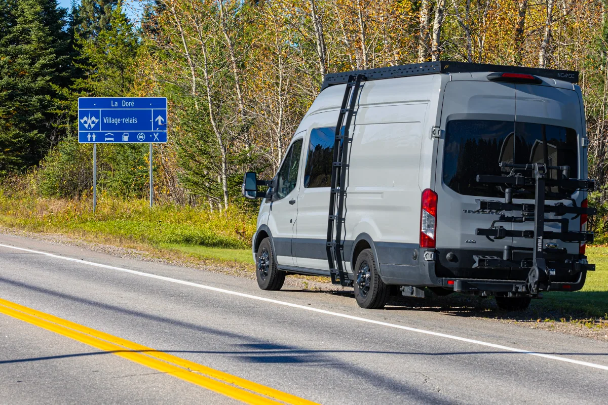Van blanc garé sur la route 167 près du panneau du village-relais de La Doré